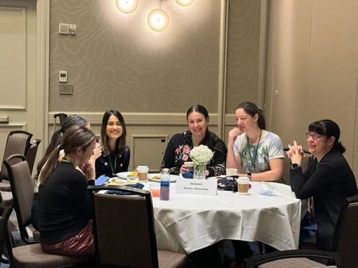 Miembros sentados alrededor de una mesa conversando en un evento del capítulo